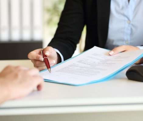 Close up of an executive hands holding a pen and indicating where to sign a mortgage at office after mortgage processing