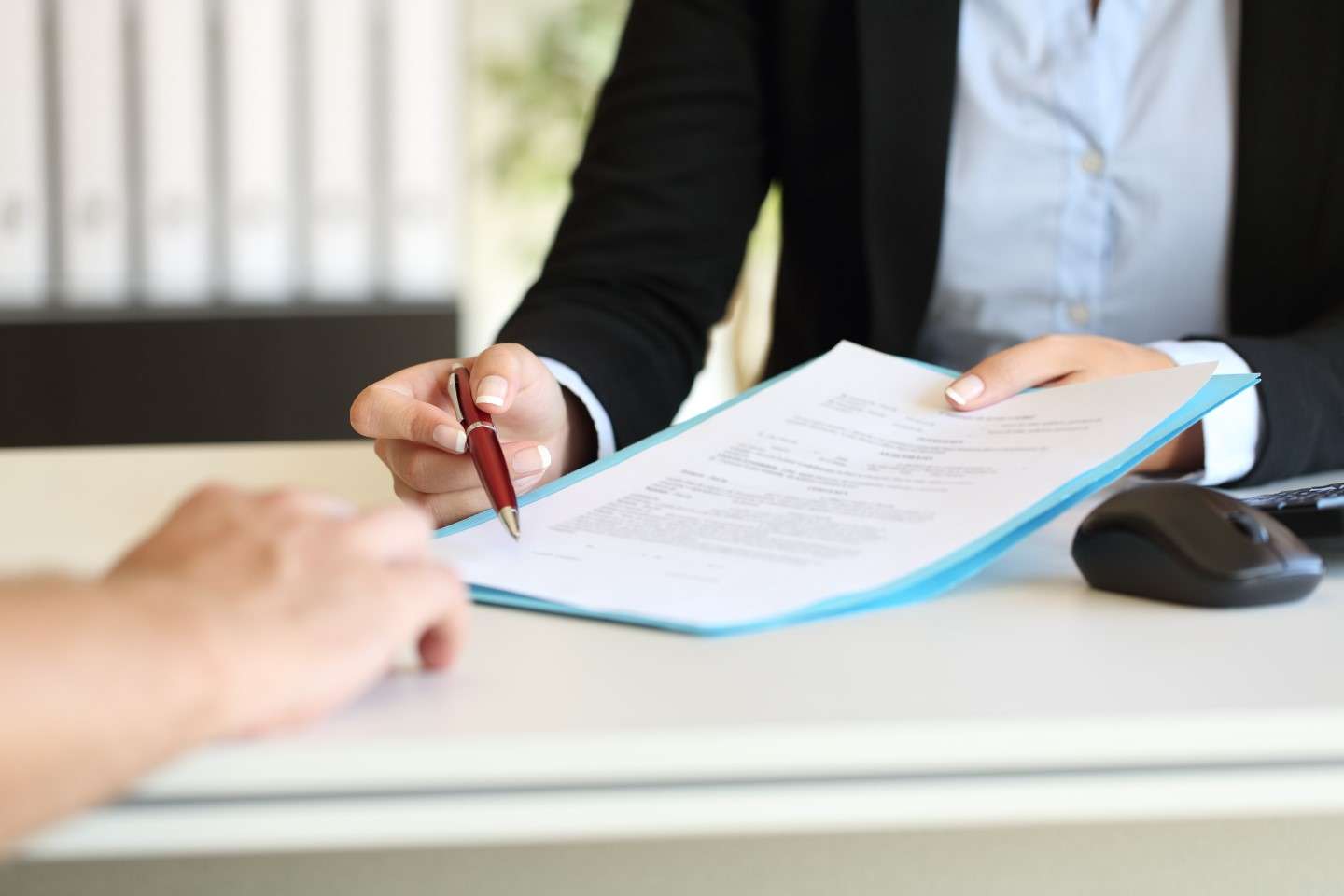 Close up of an executive hands holding a pen and indicating where to sign a mortgage at office after mortgage processing